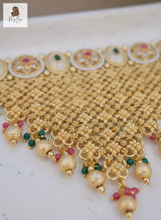 Gold necklace with beads and colorful accents on a white background