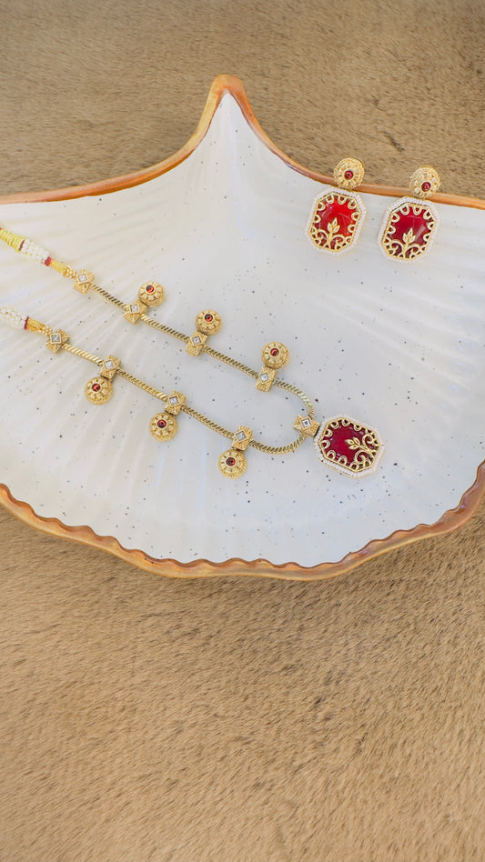 Hey Bae ruby red and gold geometric necklace set on a beige surface