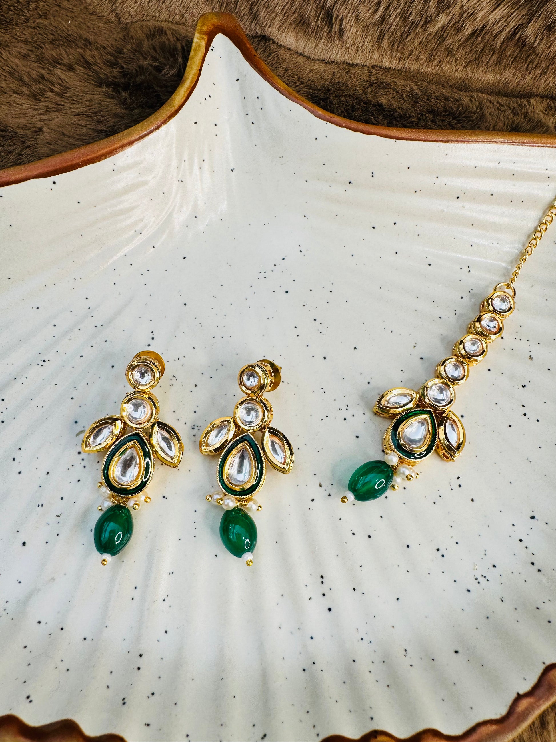 Kundan earrings and tikka on white shell plate
