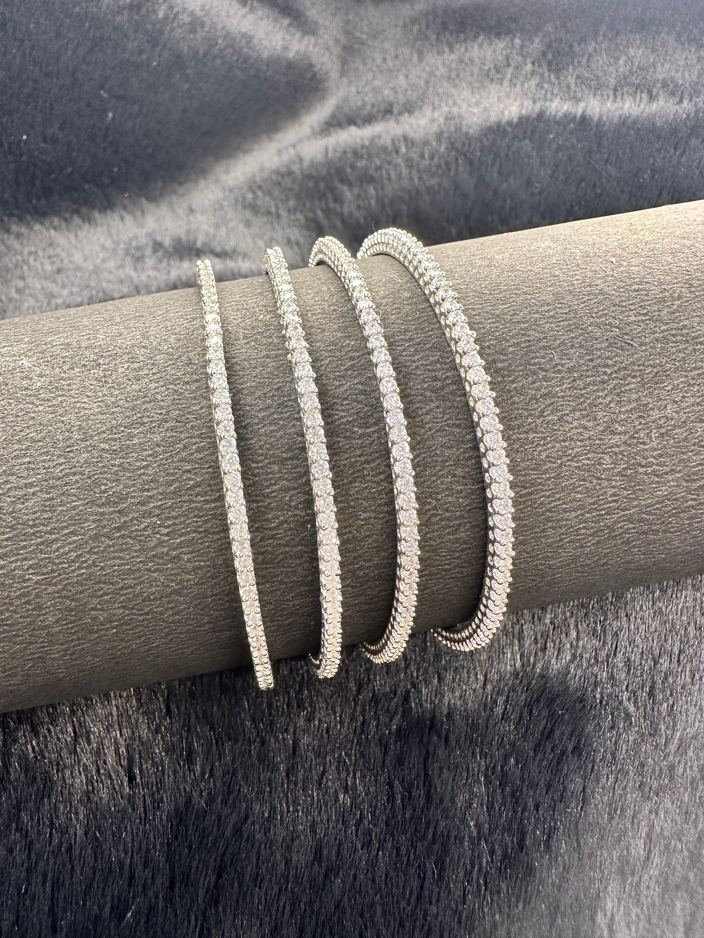 Flat lay photo of American Diamond bangles set of 4 on golden fabric background