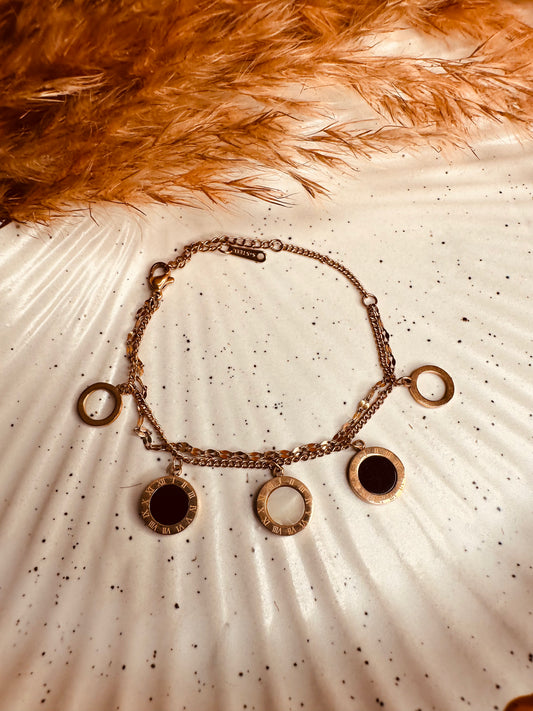 Close-up of black and white Roman numeral charms on HeyBae gold bracelet