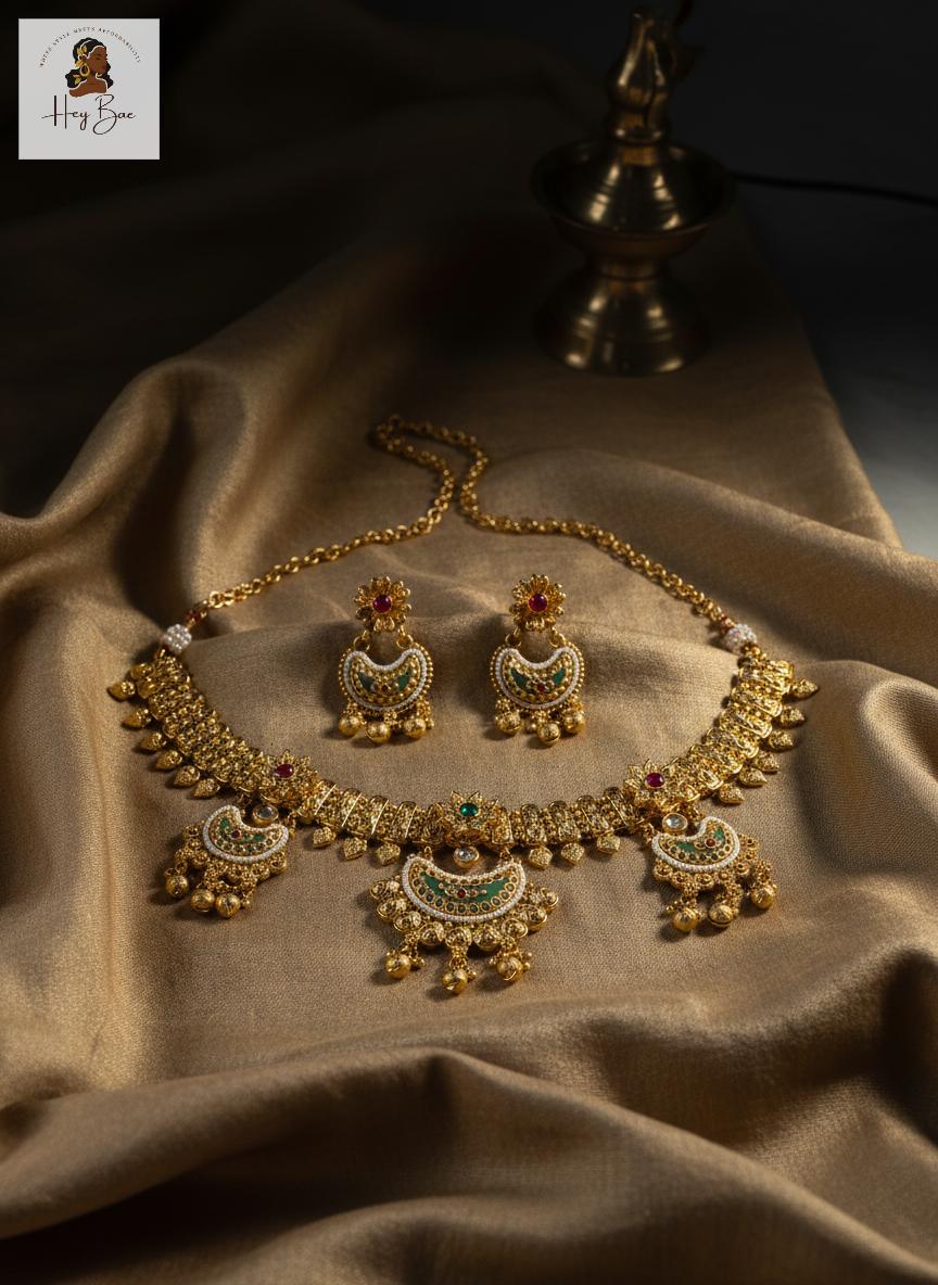 Gold necklace and earrings set on a brown fabric background