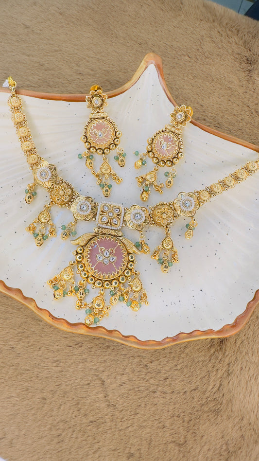 Gold necklace and earrings set on a decorative plate with a beige background