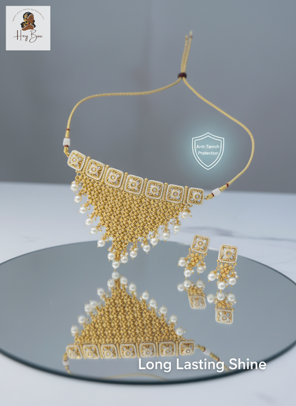 Gold necklace and earrings set on a reflective surface with 'Long Lasting Shine' text.