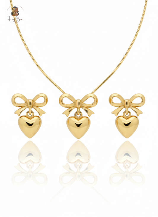 Gold bow and heart pendant necklace and earrings on a white background