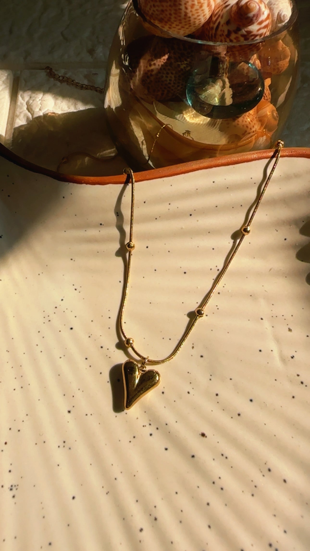 Gold necklace with a heart pendant on a textured surface