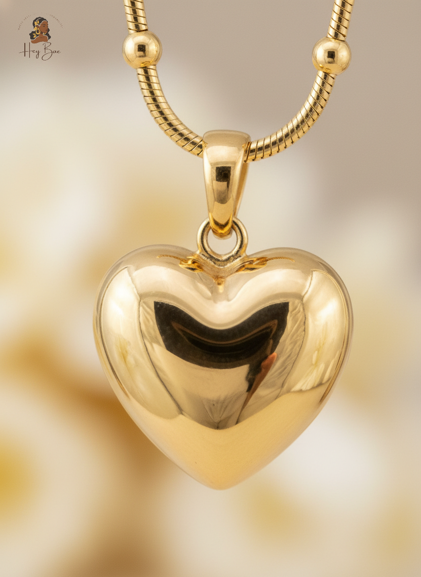 Gold heart-shaped pendant on a gold chain against a gold background