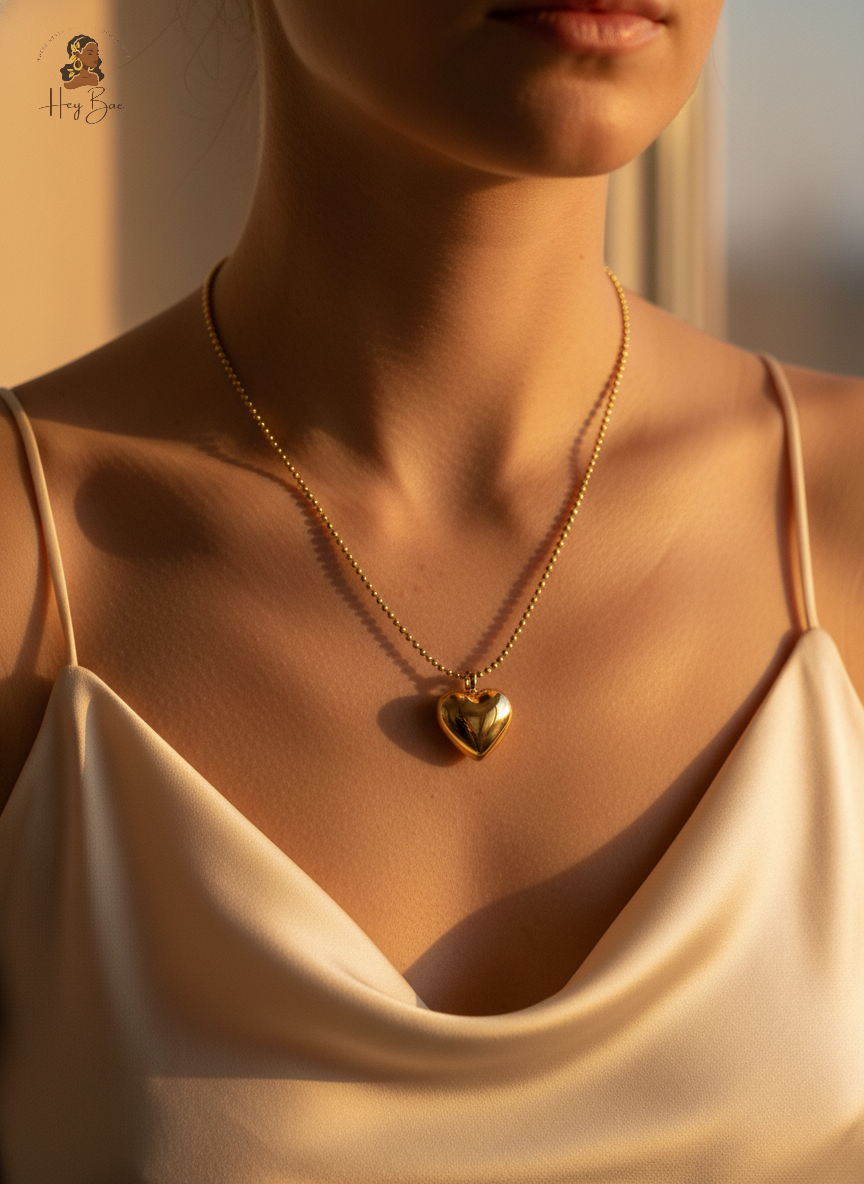 Woman wearing a gold necklace with a heart pendant, soft focus on background