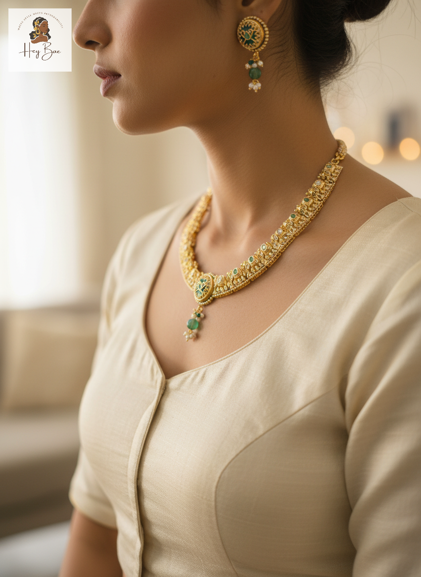 Woman wearing a gold necklace with green gemstones and matching earrings.