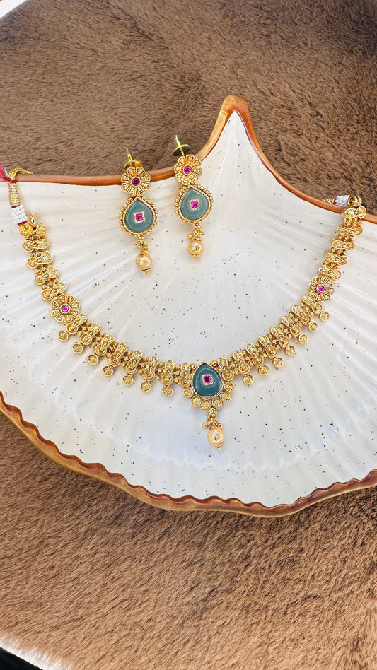 Gold necklace and earrings set on a seashell