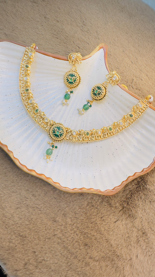 Gold necklace with green gemstones on a white shell