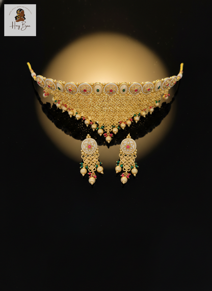 Ornate gold necklace with matching earrings on a reflective surface