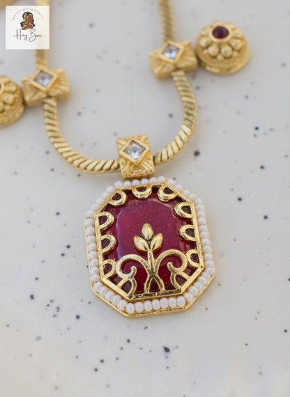 Hey Bae ruby red and gold geometric necklace set on a speckled background