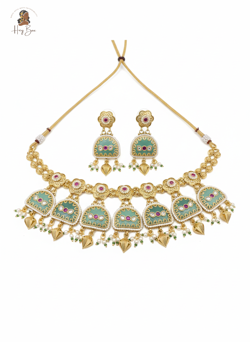 Ornate necklace and earrings set with gold and gemstone details on a white background.