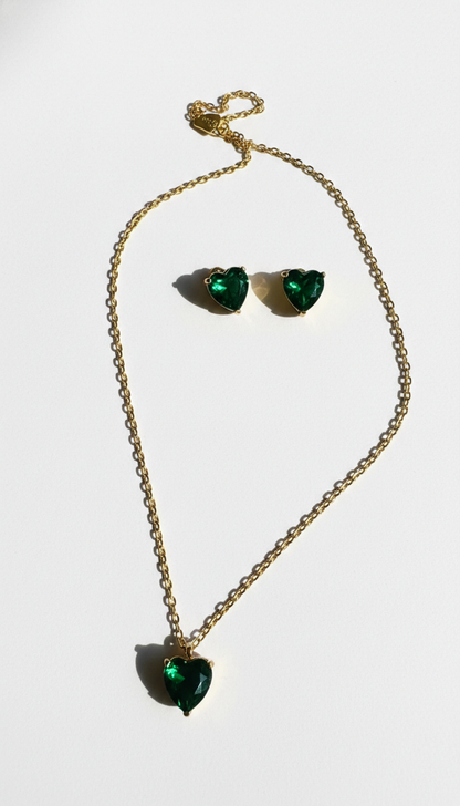 Pendant and heart-shaped earrings with green gemstones on a white background