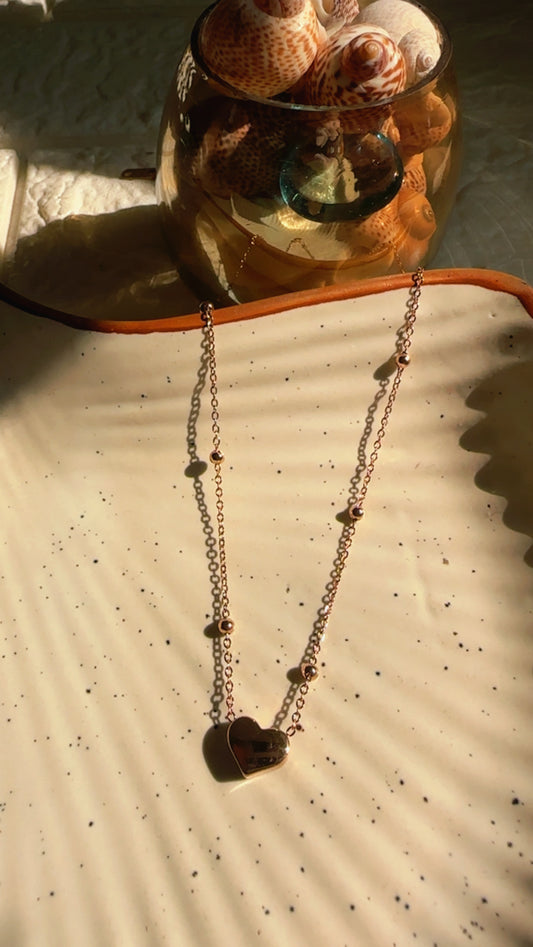 Pendant with heart pendant on a textured surface