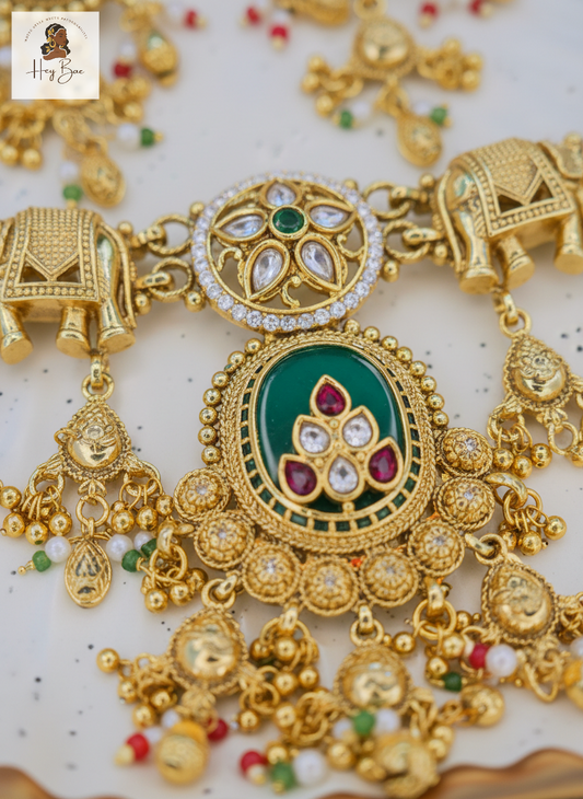 Ornate gold necklace with green gemstone centerpiece on a white background