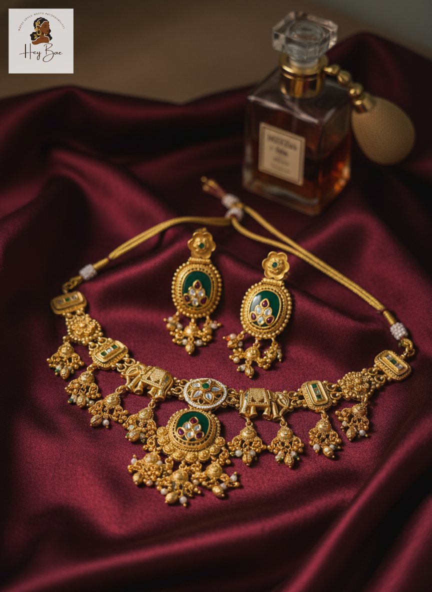 Royal Elephant Motif Antique Gold Choker Set with Green Stones with a perfume bottle on a dark fabric background