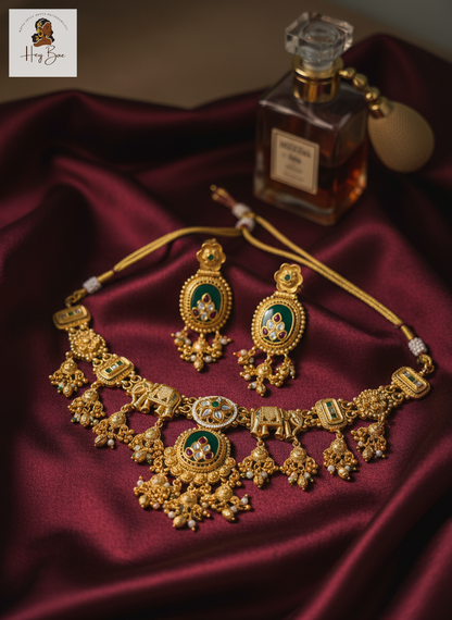 Royal Elephant Motif Antique Gold Choker Set with Green Stones with a perfume bottle on a dark fabric background