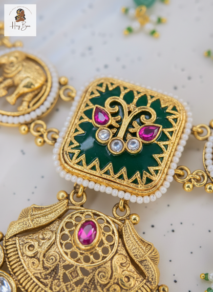 Decorative gold and green jewelry piece with pink gemstones on a light background