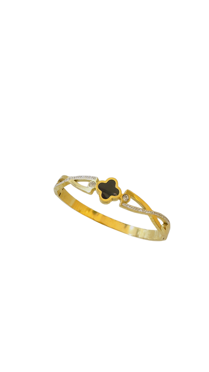 Gold bracelet with a black clover-shaped center on a white background