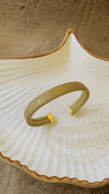 Gold bracelet on a textured ceramic dish