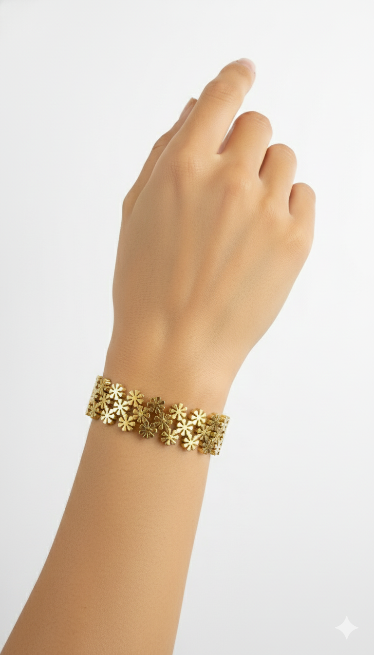 Gold bracelet with floral designs on a wrist against a white background