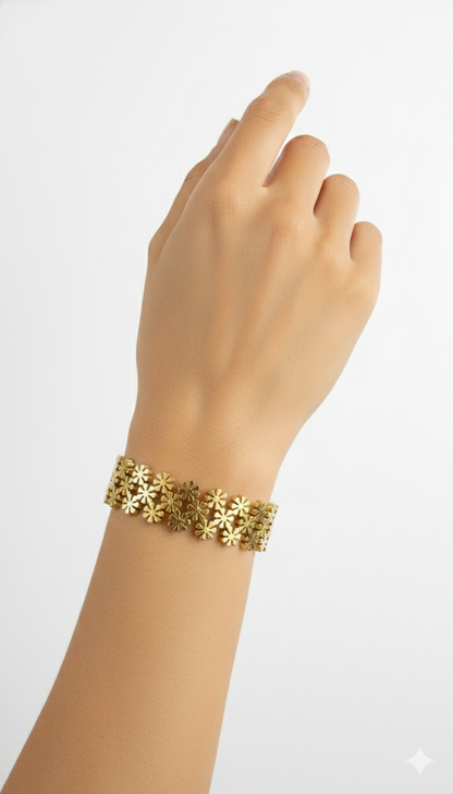 Gold bracelet with floral designs on a wrist against a white background