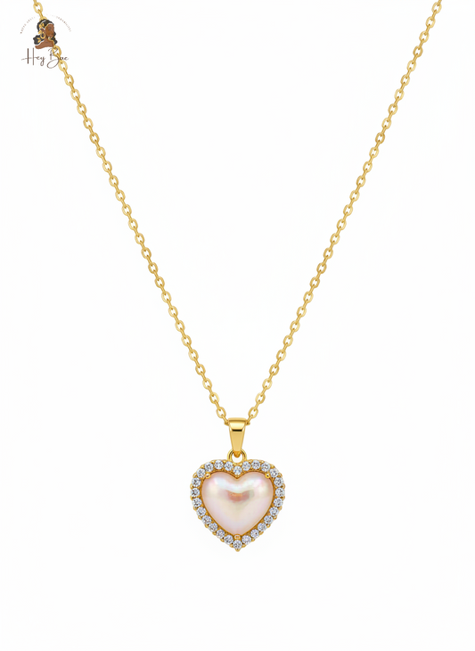 Gold necklace with a heart-shaped pink pendant on a white background