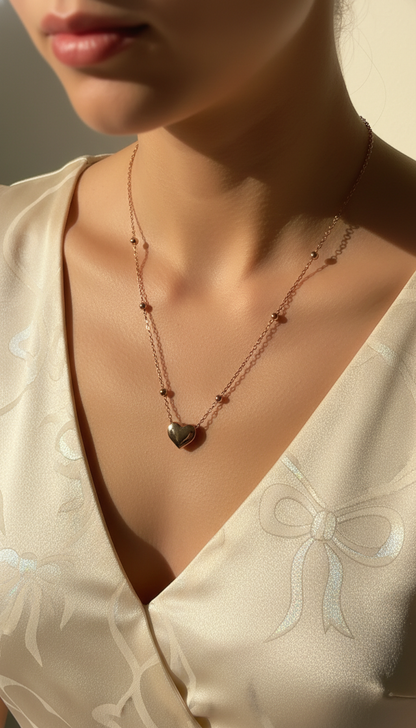 Necklace with a heart pendant worn by a person in a white garment.