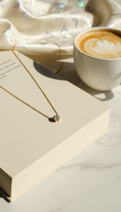 Gold necklace on an open book with a cup of coffee in the background