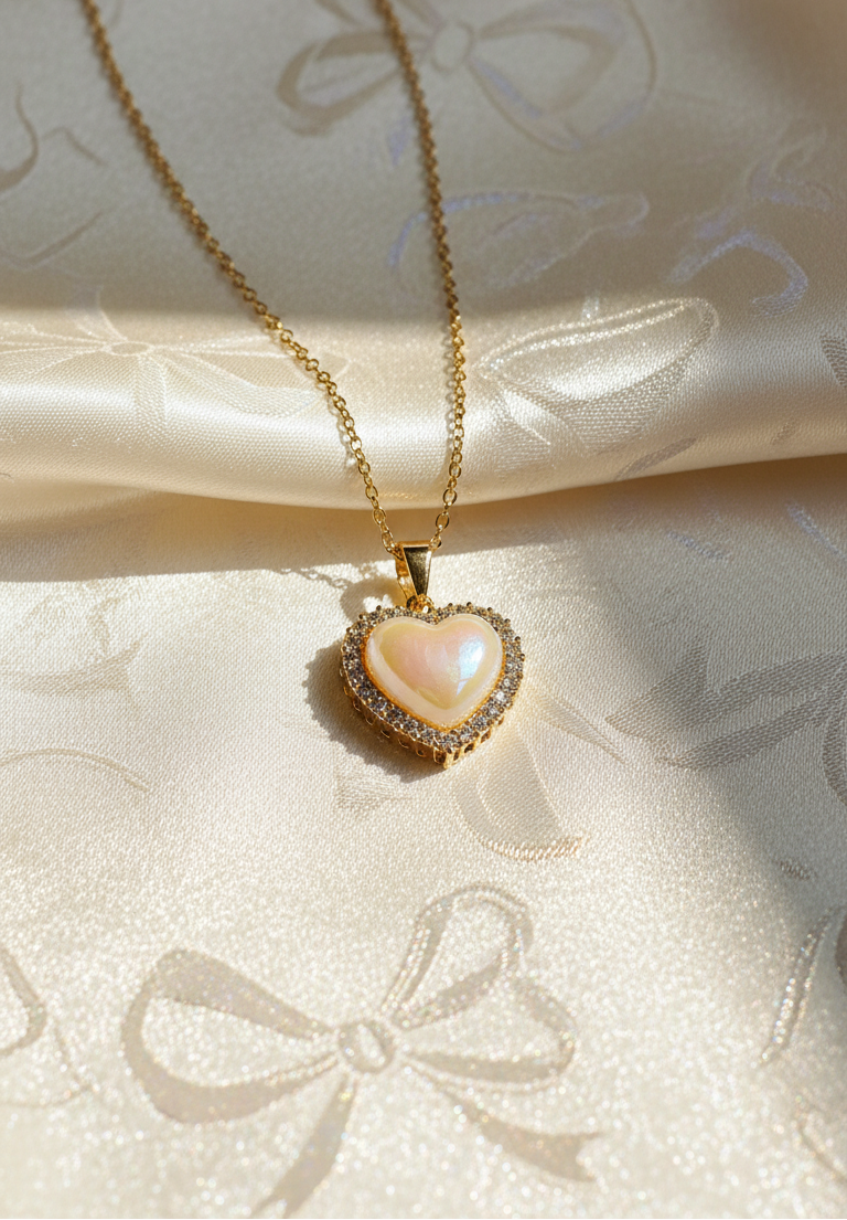 Heart-shaped pearl pendant necklace on a soft fabric background with 'JewelDen' branding.