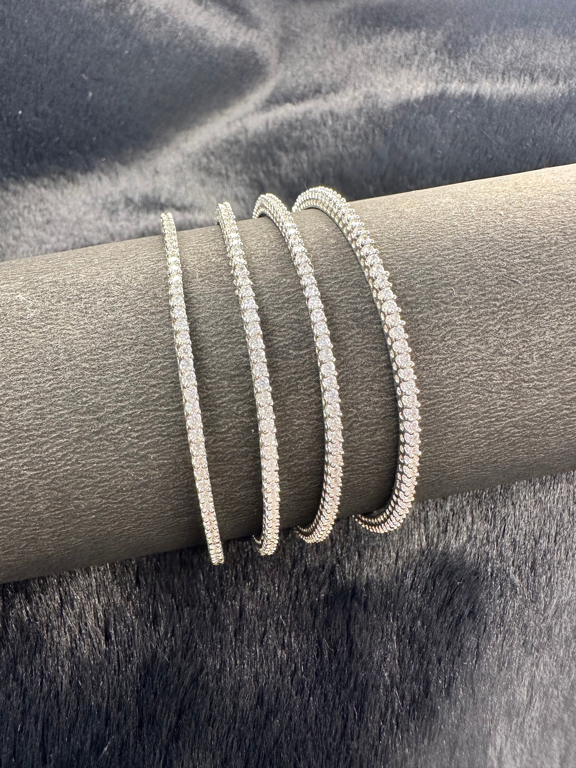 Flat lay photo of American Diamond bangles set of 4 on golden fabric background