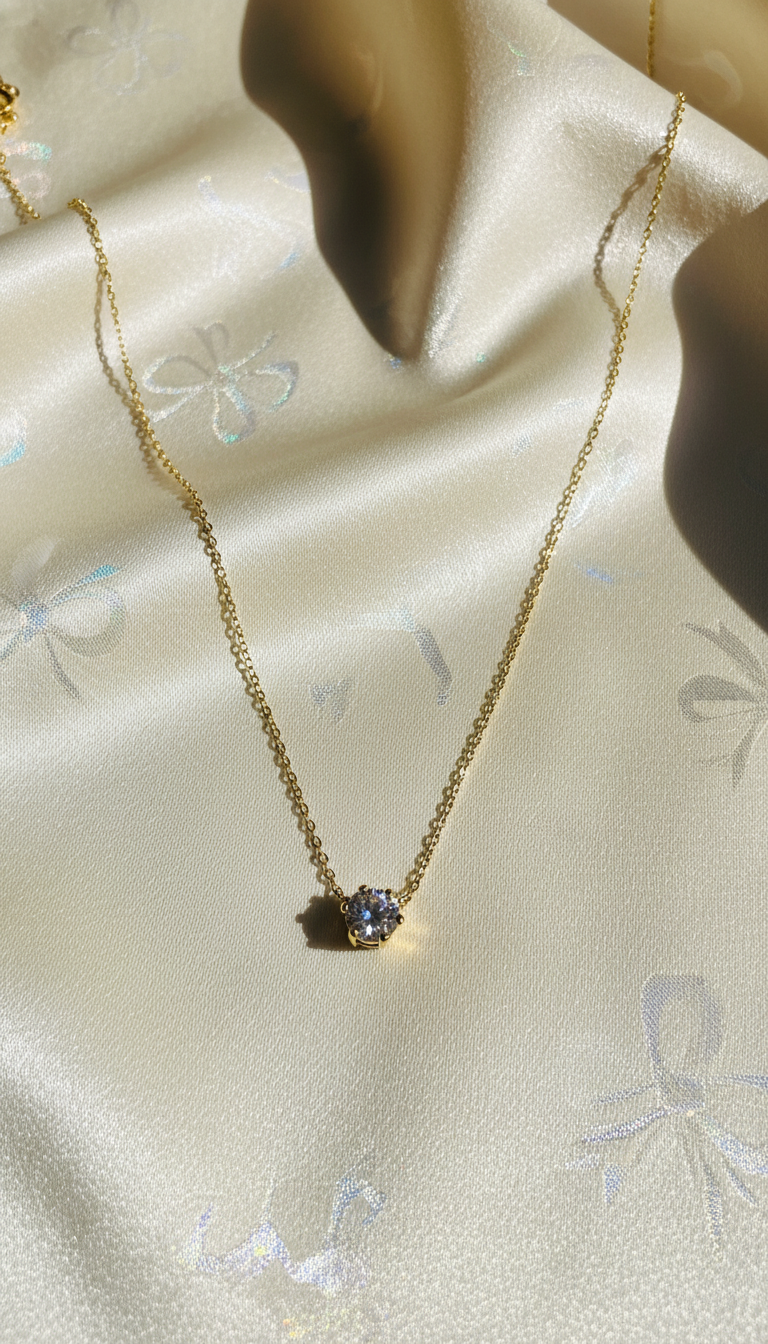 Gold necklace with a blue gemstone on a light fabric background
