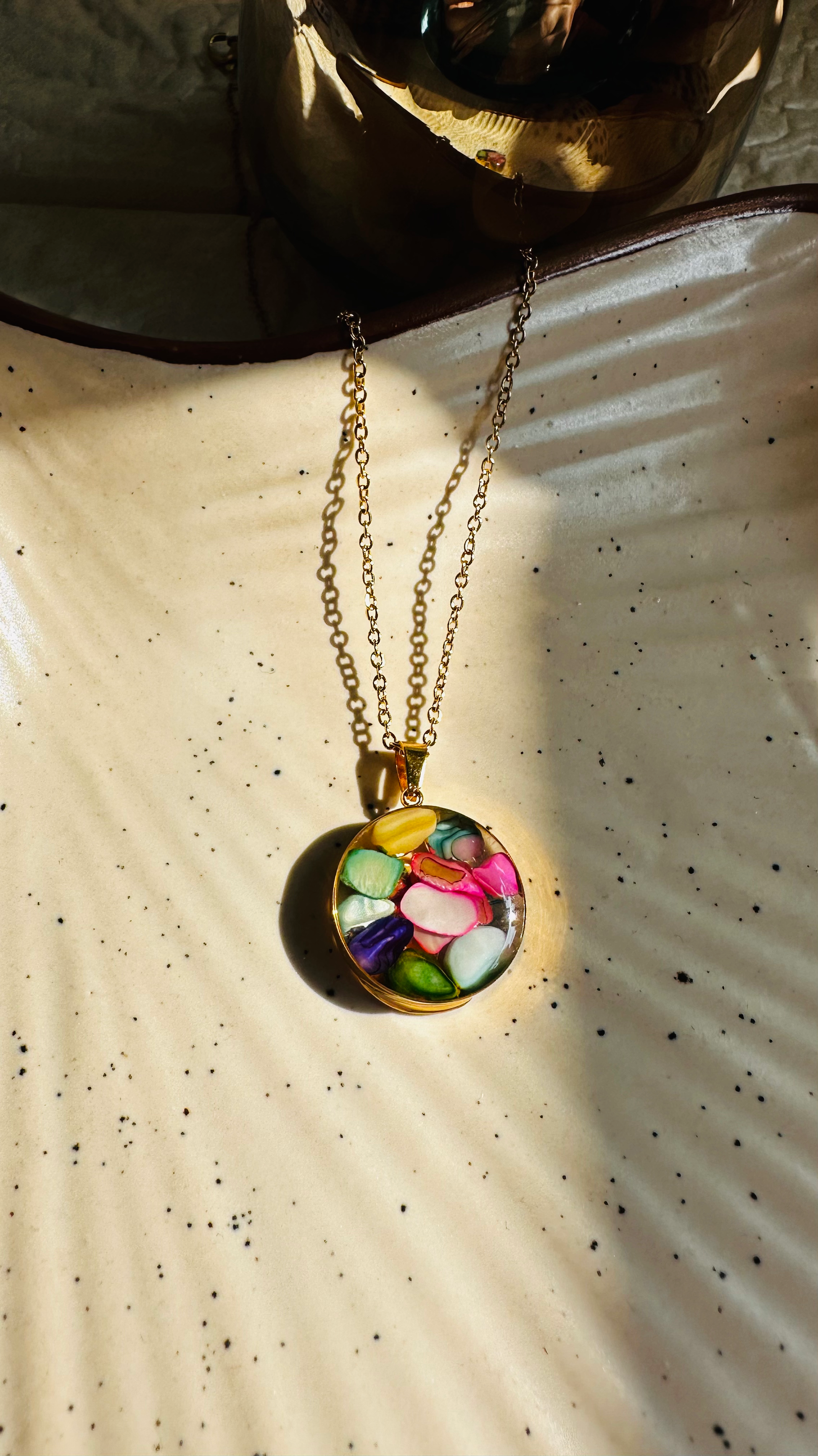 Necklace with a colorful pendant on a textured beige surface