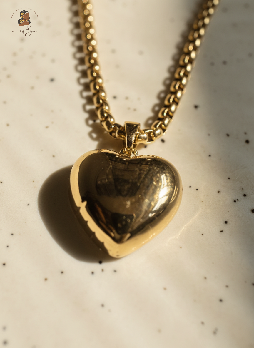 Gold heart-shaped pendant on a chain against a speckled background
