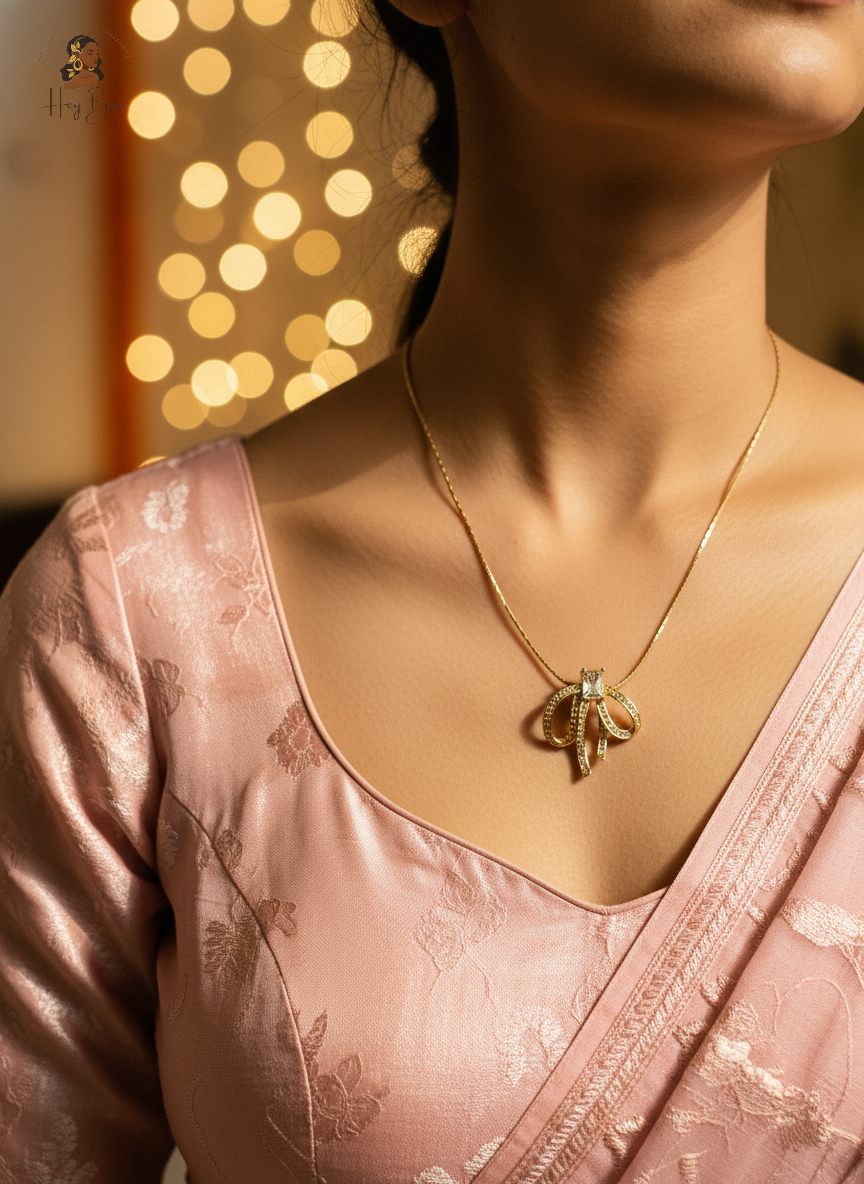 Person wearing a pink saree with a gold necklace against a blurred bokeh background