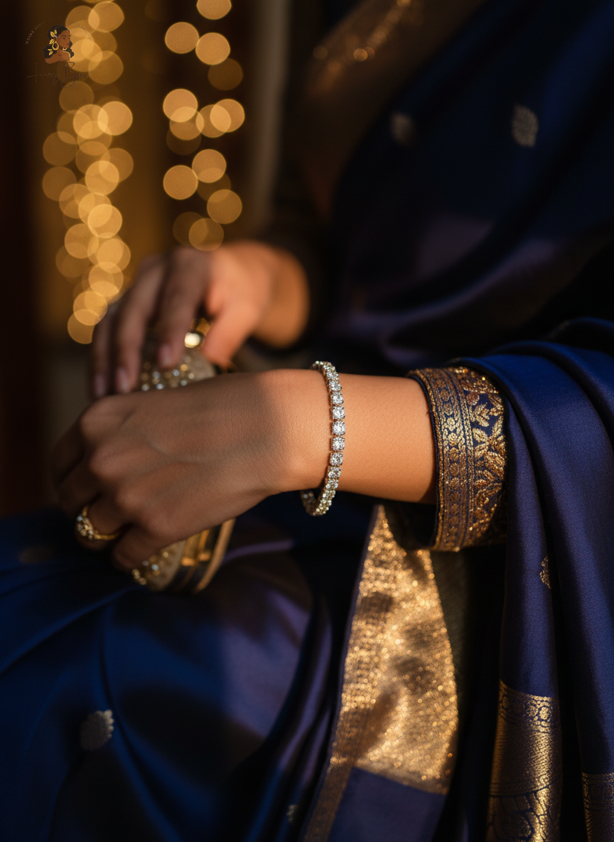 Person wearing a blue saree with gold border and bracelet, blurred lights in the background