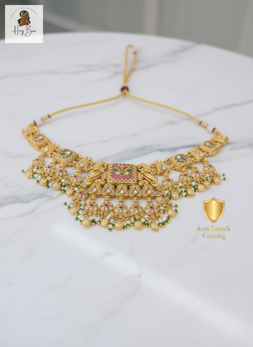 Gold necklace with gemstones on a white surface, featuring 'Hari Bhoomi' branding.