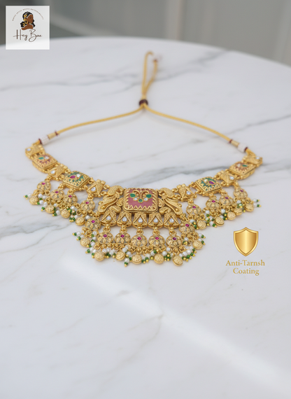 Gold necklace with gemstones on a white surface, featuring 'Hari Bhoomi' branding.