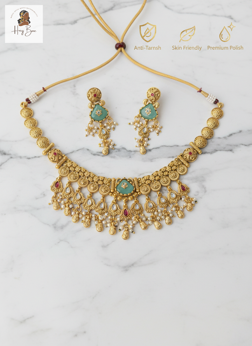 Gold necklace and earrings set on a marble background with Huggz logo.